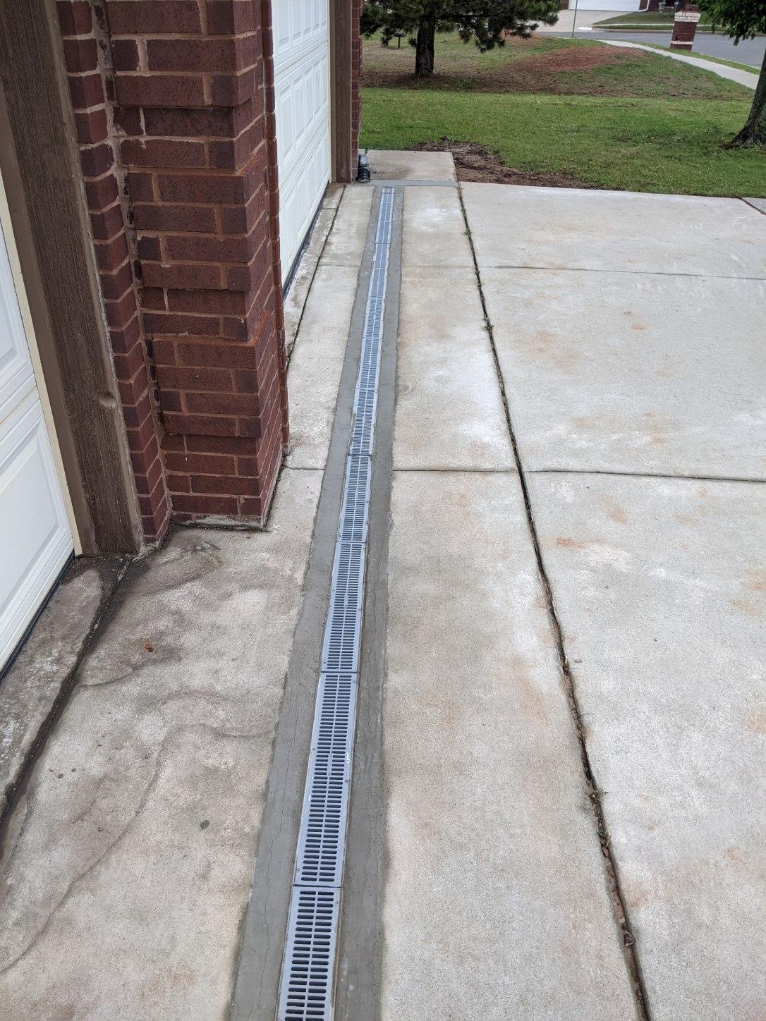 NDS Grey Composite Channel Drain Running Across Driveway Connected to 4 Inch ADS Solid Drain Pipe